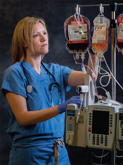 Dr. Nicole Guinn standing next to a blood infustion machine