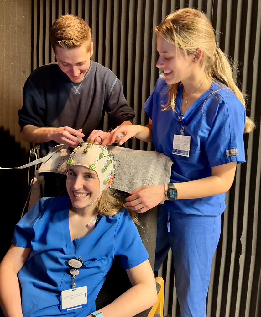 Travis Larson, Dr. Leah Acker & Sloan Soyster Heinz performing an EEG in the lab
