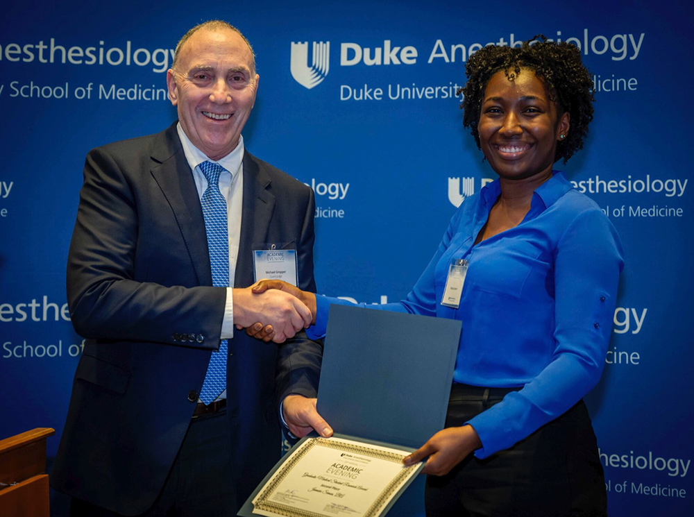 Melissa Adams shaking hands with visiting judge Dr. Michael Gropper after winning 2nd place in graduate/medical student research category