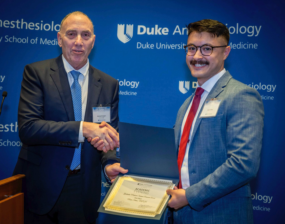 Noah Timko shaking hands with Dr. Michael Gropper after winning 1st place in graduate/medical student research category