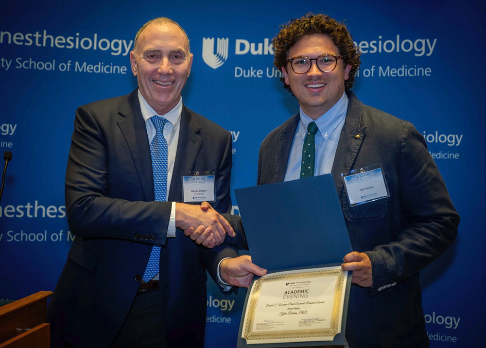 Dr. Tyler Reekes (First place in Post-doctoral research category) shaking hands with visiting judge Dr. Michael Gropper