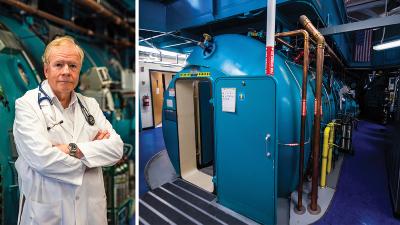 Dr. Richard Moon pictured next to a hyperbaric chamber.