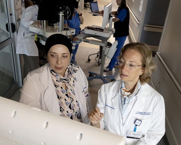 Dr. Sajdeya and Dr. Treggiari review charts in the Neuro ICU