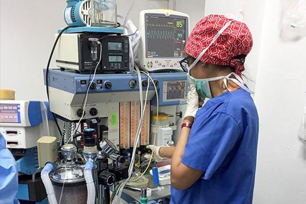 Anushree Doshi, MD standing next to anesthesia equipment.