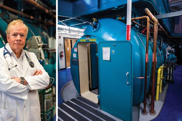 Dr. Richard Moon pictured next to a hyperbaric chamber.