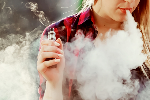 Woman vaping an e-cigarette device.